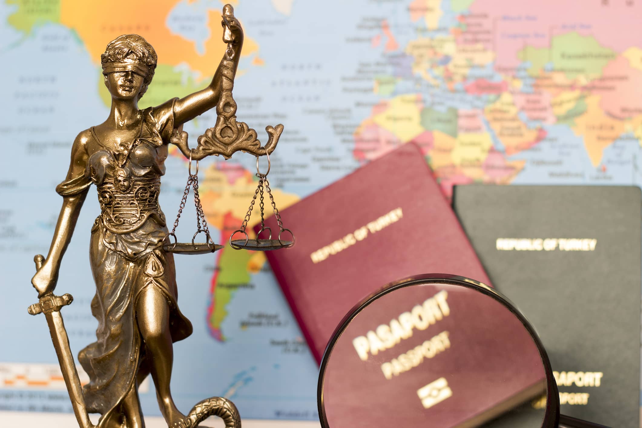 A statue of Lady Justice stands in front of a world map and passports, symbolizing international divorce and the legal complexities for individuals married in India seeking divorce in Canada.