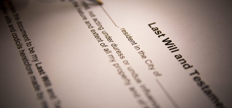 Close-up of a pen poised over a will document, the heading 'Last Will' visible and blurred text around it.