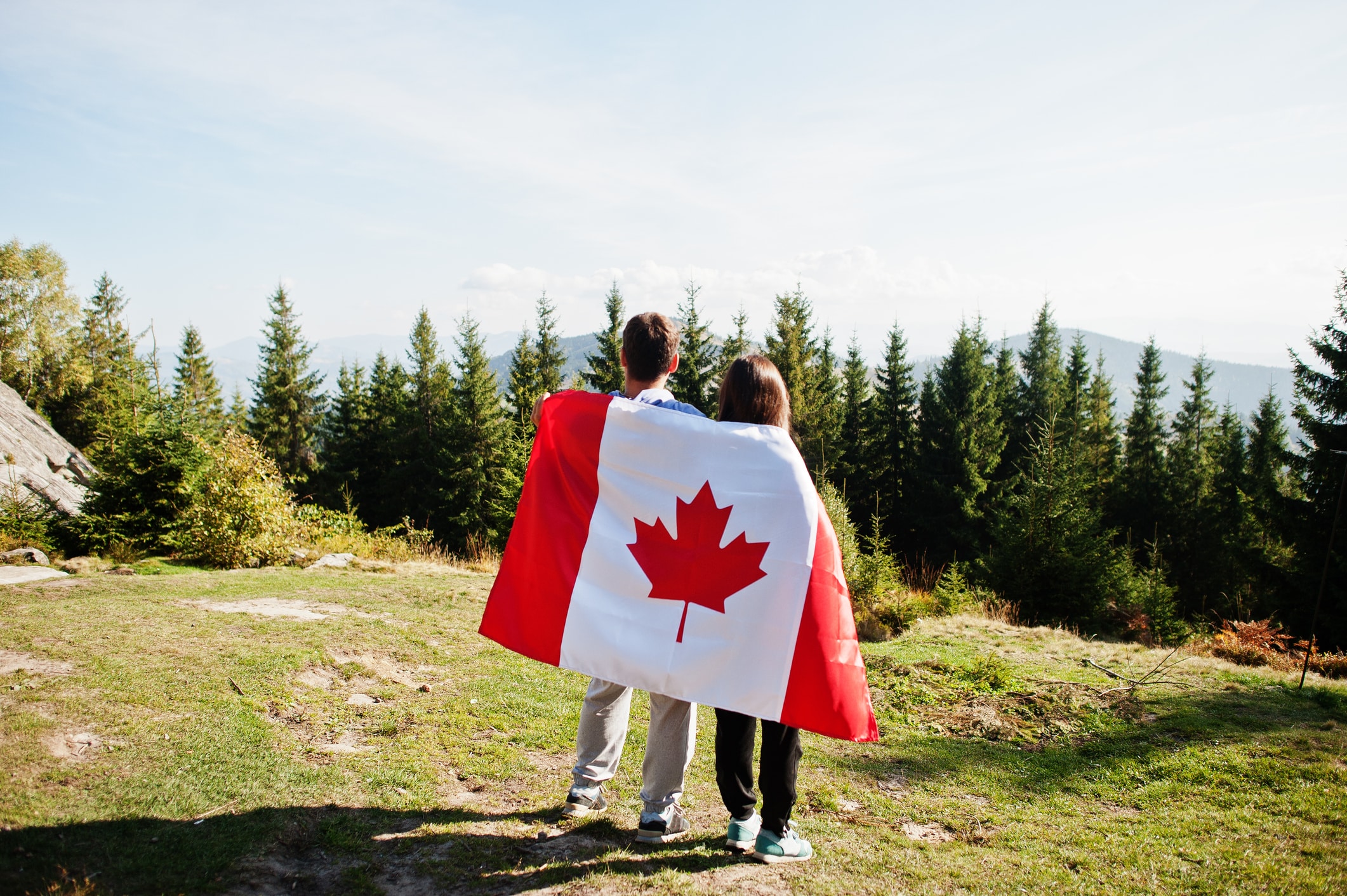 Happy Canada Day Couple with large Canadian flag celebration in mountains