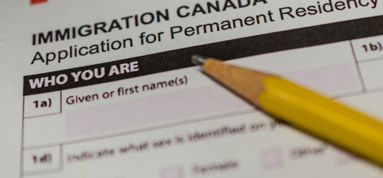 Close-up of a pencil pointing to the 'WHO YOU ARE' section on a Canada Immigration form for permanent residence application.